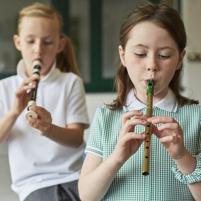 Schoolgirls playing recorders in classroom at primary school